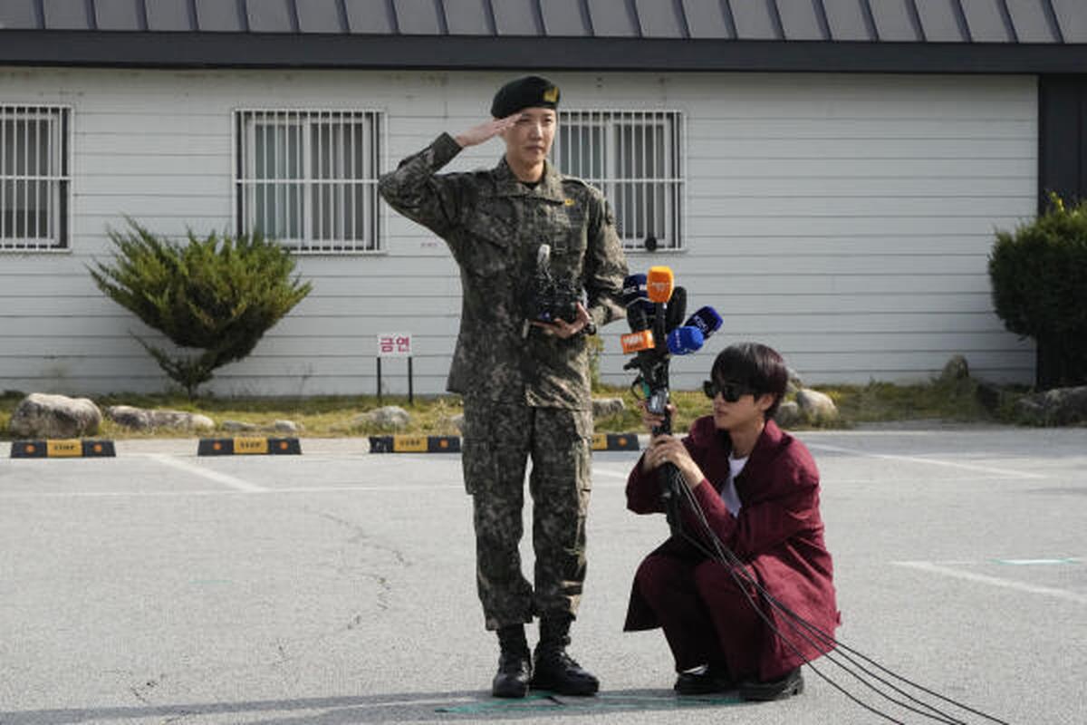 K-pop band BTS member J-Hope, center, salutes as fellow member Jin holds microphones after being discharged from a mandatory military service outside of an army base in Wonju, South Korea, Oct. 17, 2024. (AP Photo/Ahn Young-joon)